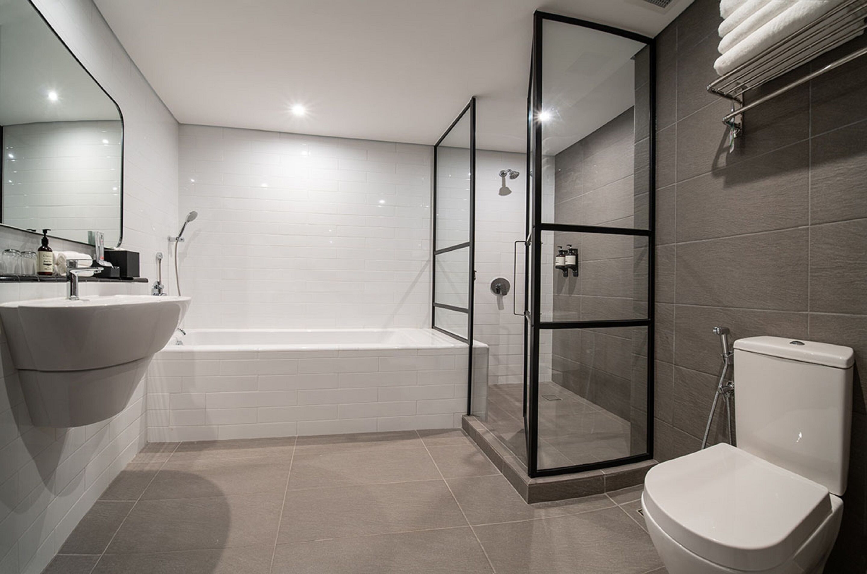 A modern bathroom with a white sink, bathtub, glass-enclosed shower, and toilet.