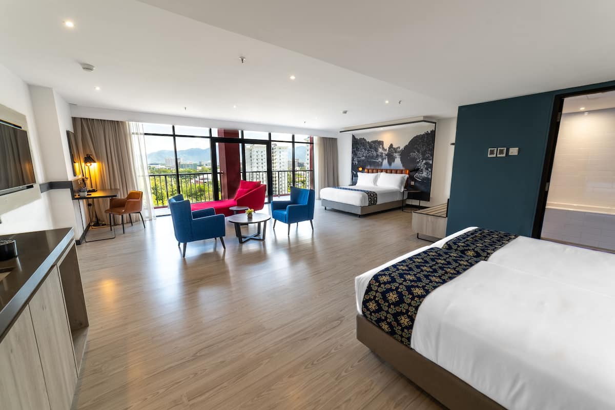 A modern hotel room with a large bed, a dining area with a table and chairs, and a balcony with a view of the city.
