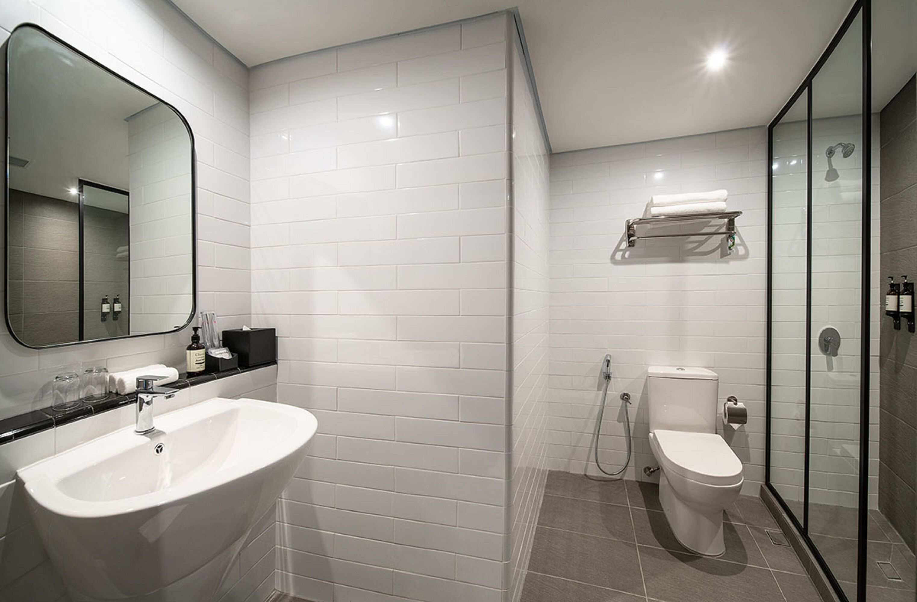 Ein modernes Badezimmer mit einem weißen Waschbecken, einer Toilette und einer Duschkabine aus Glas.