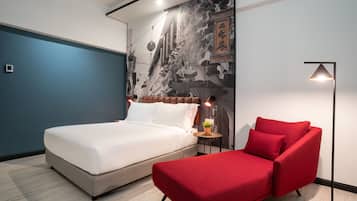 Un dormitorio moderno con cama, sofá rojo, mesita de noche y un mural en la pared.
