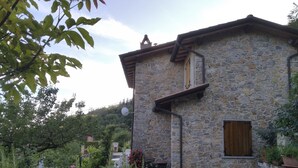 Une maison en pierre avec une allée en gravier, une porte en bois et une antenne parabolique.