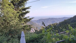 Un jardin agrémenté d’une pergola, offrant une vue sur une vallée et, au loin, sur une chaîne de montagnes.
