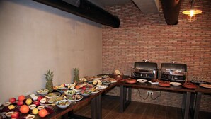 Una mesa de buffet con diversos platos y una pared de ladrillo al fondo.
