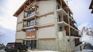 Un hotel con fachada de piedra, balcones de madera y un letrero en idioma extranjero.