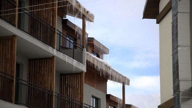 Un edificio de varios pisos con balcones de madera y barandillas de metal.