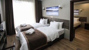 Habitación de hotel con dos camas, un escritorio y un amplio ventanal con cortinas.
