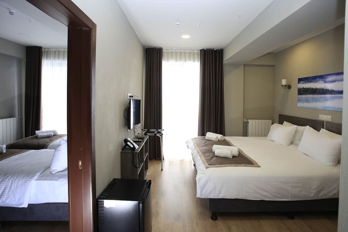 A hotel room with two beds, a desk with a telephone, a television, and a painting on the wall.