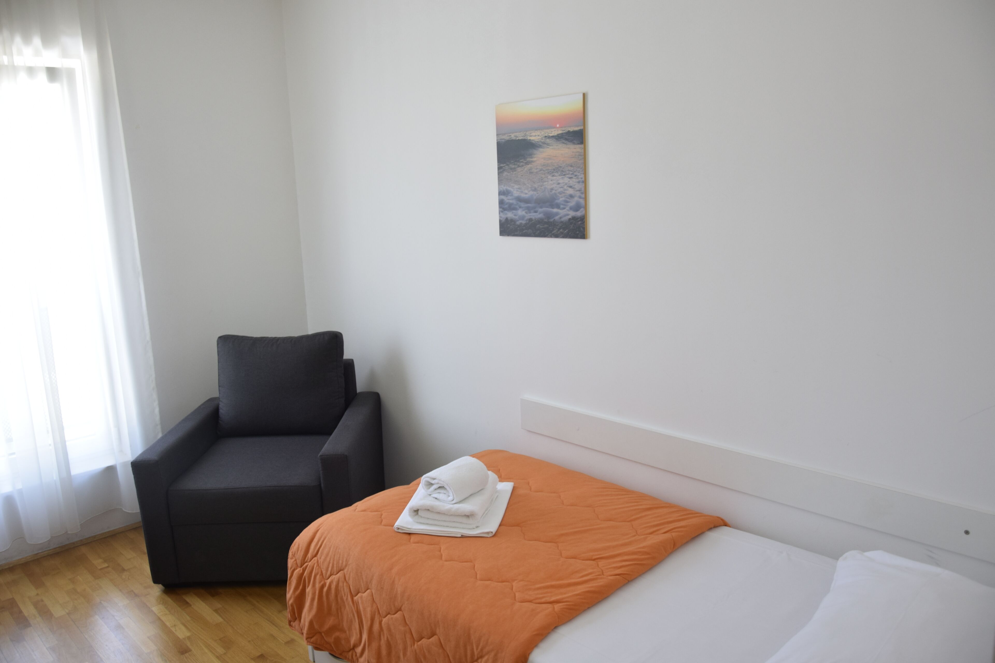 Une chambre d’hôtel avec un lit, une chaise et un tableau au mur.