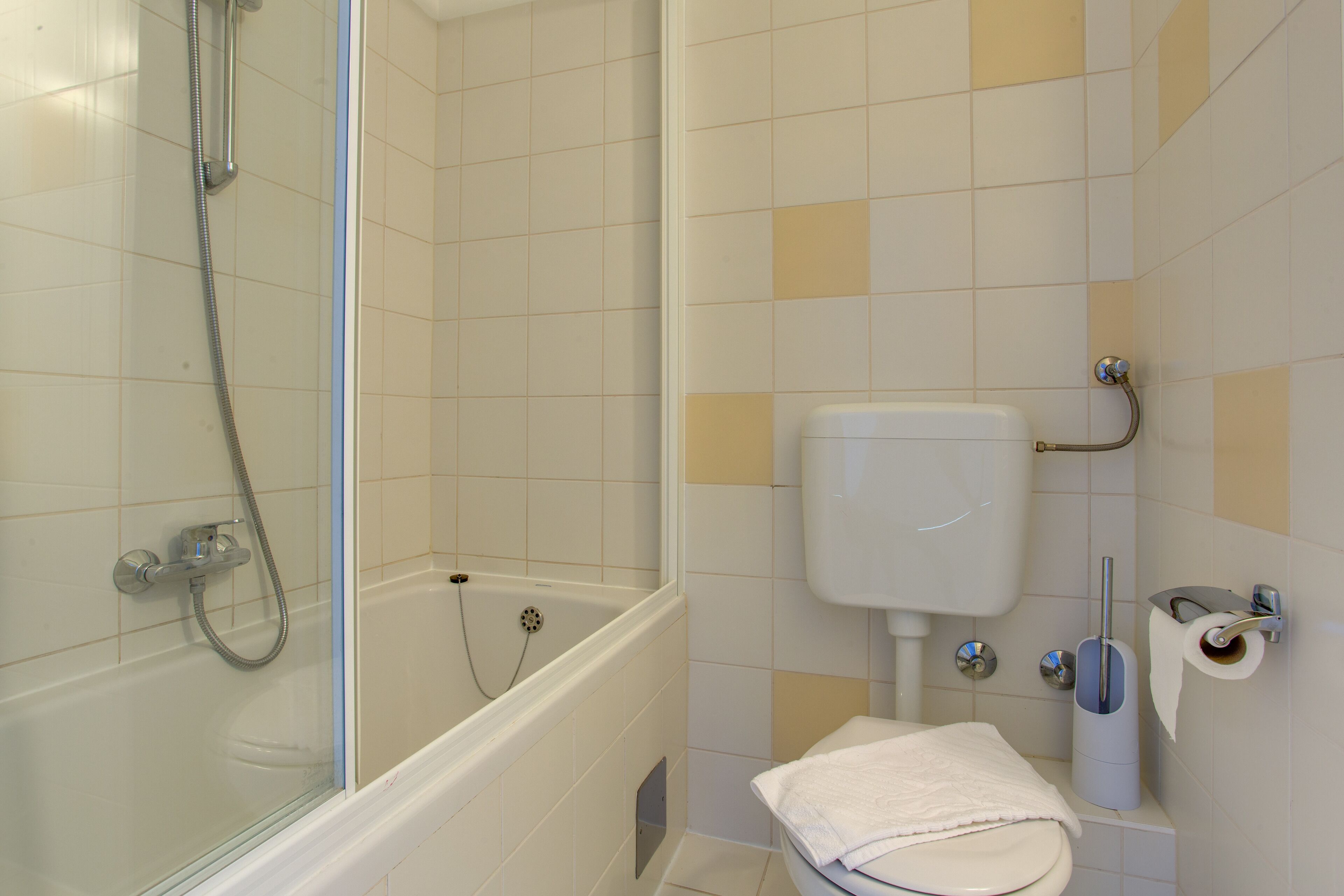 A bathroom with a glass-enclosed shower, a bathtub, and a toilet.