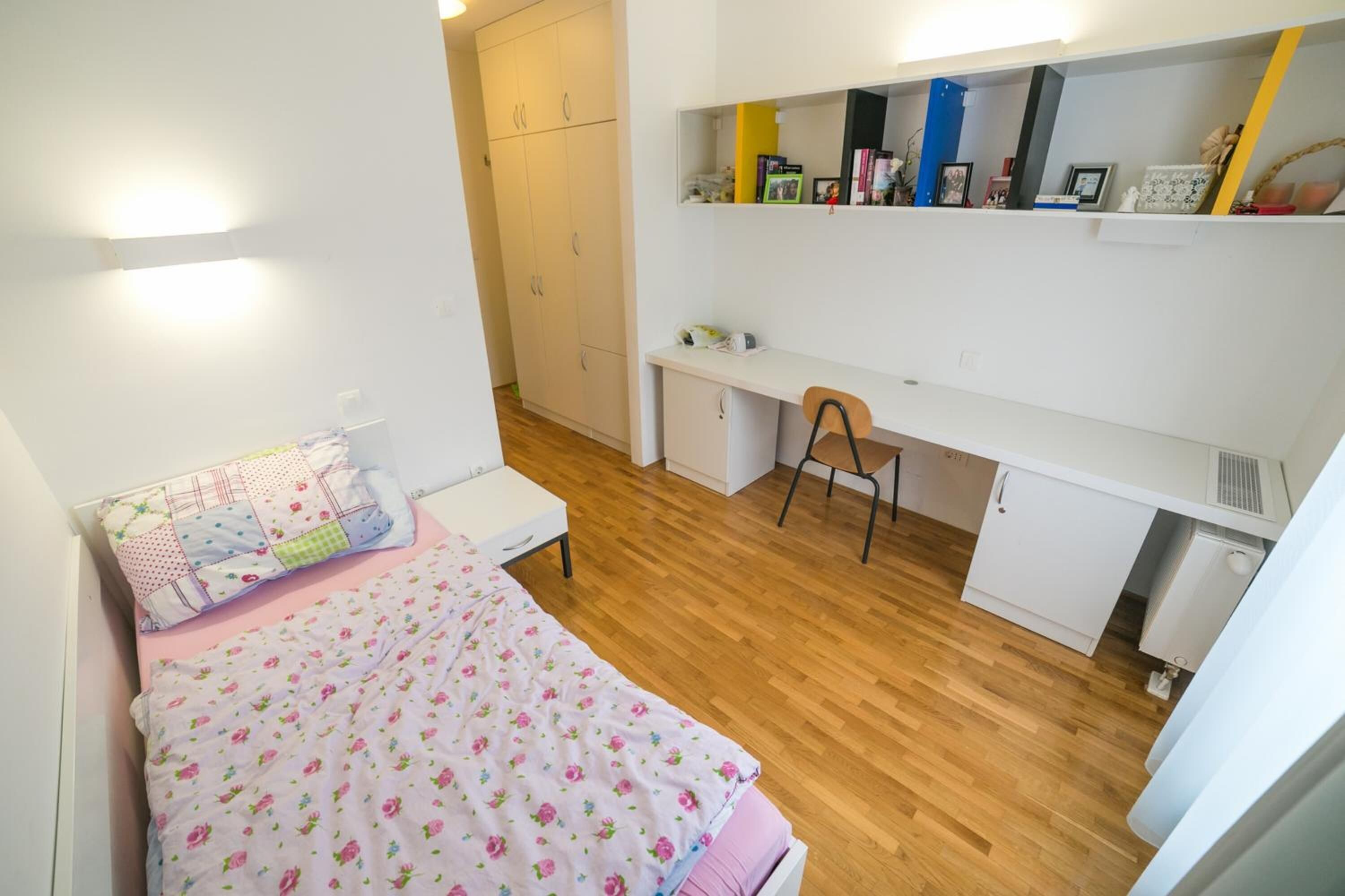 A bedroom with a bed, a desk, a chair, and a wardrobe.