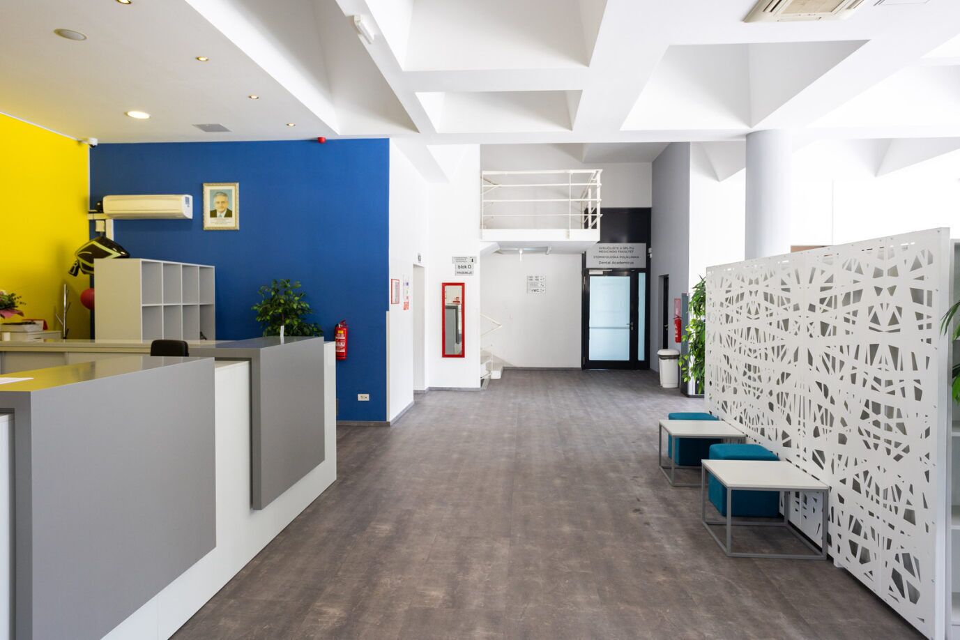 Un espace de bureau moderne doté d’un comptoir d’accueil, de murs bleus et blancs, et d’une cloison décorative.