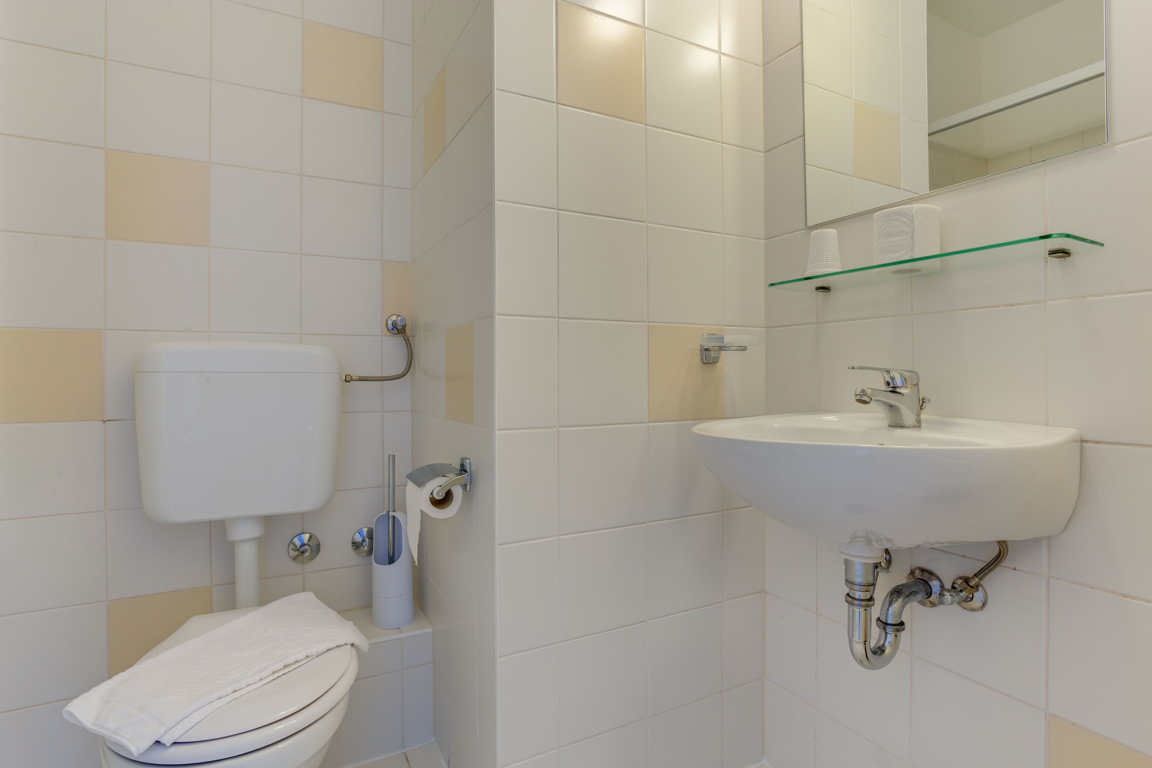 A bathroom with a toilet, sink, and mirror.