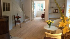 Ein geräumiges Wohnzimmer mit Treppe, einem Essbereich mit Tisch und Stühlen sowie einem Bücherregal.
