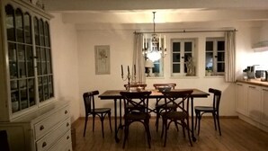 Ein Esszimmer mit Holztisch und -stühlen, einer Kristallleuchtre und einer Vitrine mit Glastüren.