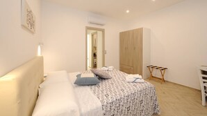 A bedroom with a bed, a wardrobe, a desk, and an air conditioning unit.