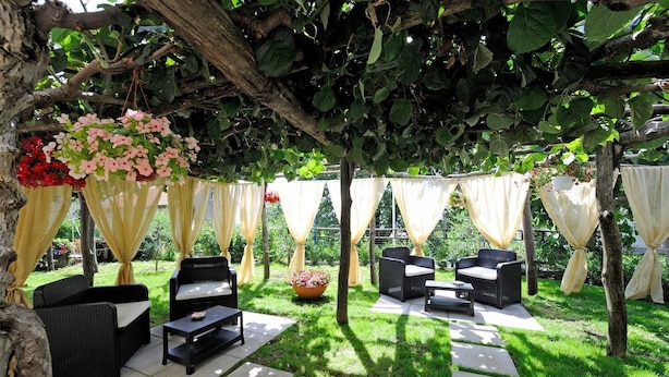 An outdoor patio with wicker furniture, a stone pathway, and hanging flower baskets.