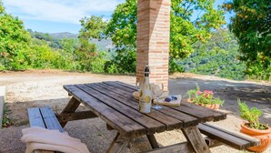 A picnic table with a bottle, glasses, and sunglasses. - Casa Rural Molino de la Máquina Cartajima by Ruralidays (Málaga)
