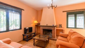 A living room with a fireplace, a television, and a sofa. - Casa Rural Molino de la Máquina Cartajima by Ruralidays (Málaga)