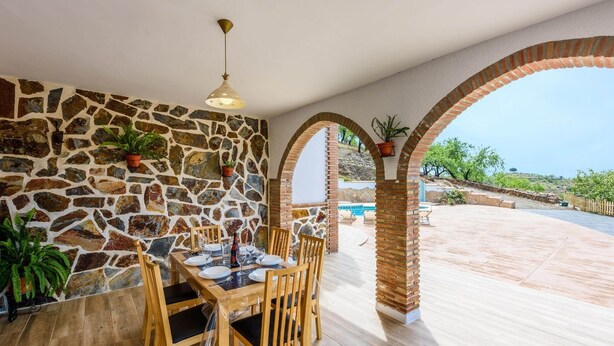 Un coin repas avec un mur en pierre, une table en bois et des chaises.