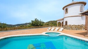Ein Pool mit Liegestühlen, eine Steinmauer und ein weißes Gebäude mit einem Turm.