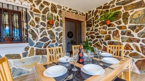 Un coin repas aux murs de pierre, avec une table dressée pour quatre personnes, comprenant des verres à vin et des assiettes.