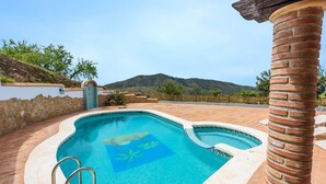 Une piscine à bord incurvé, un mur en pierre et une vue sur une montagne.