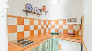 A kitchen with a checkered tile backsplash, a microwave, a sink, and a stove. - Estudio Juzcar Júzcar by Ruralidays (Málaga)