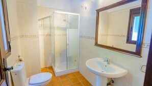 A bathroom with a glass-enclosed shower, a white sink, and a toilet. - Casa Genal Júzcar by Ruralidays (Málaga)