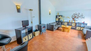 A modern living room with a fireplace, sofa, TV, and dining area. - Casa Diego Piña Júzcar by Ruralidays (Málaga)