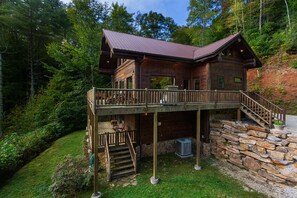 Una baita di legno con veranda, fondamenta in pietra e tetto in metallo.