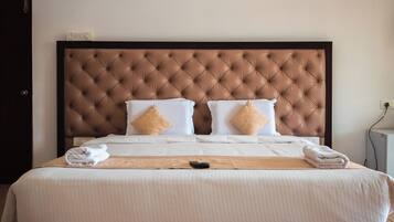 Una cama bien hecha con un cabecero capitonado, ropa de cama blanca y dos almohadas color beige.