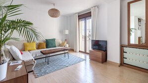 Una sala de estar moderna con un sofá, una mesa de centro, un televisor y un espejo grande.