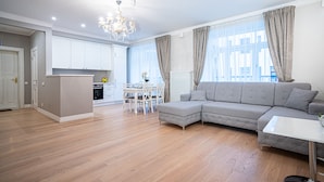 A modern living room with a grey sectional sofa, a white coffee table, and a chandelier. - WINWINSTAY Art Nouveau Lumiere Residence (Riga)