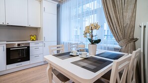 A modern kitchen with white cabinets, a Bosch oven, and a dining area with a table set for two. - WINWINSTAY Art Nouveau Lumiere Residence (Riga)
