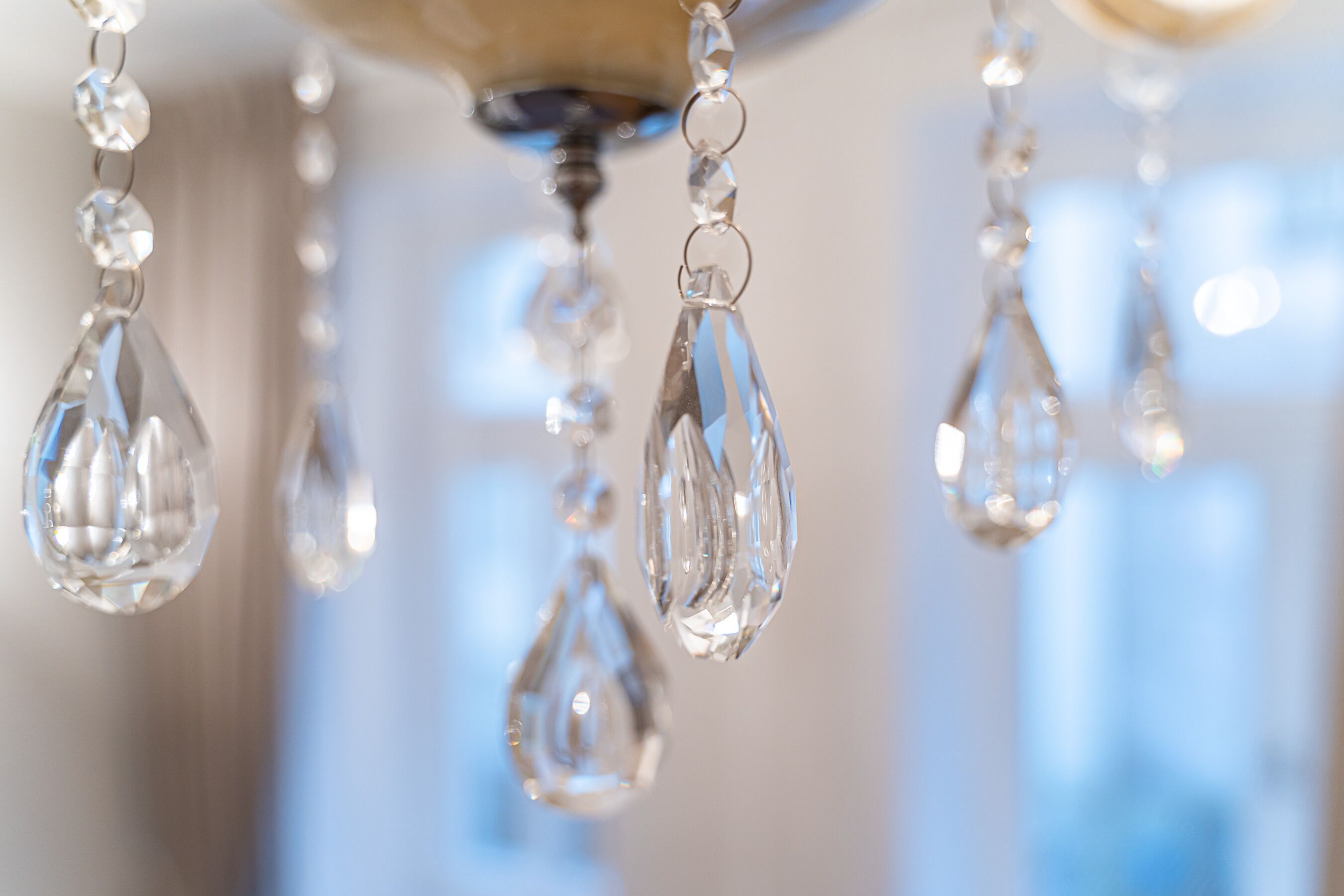 A chandelier with clear, faceted crystals hanging from a ceiling fixture.