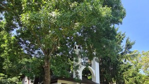 A rustic cabin with a stone foundation, a white exterior, and a large tree providing shade. - Polonezköy Country Club & Accommodation in the Wildlife Park (Beykoz)