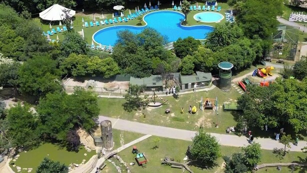 An aerial view of a resort with a large swimming pool surrounded by lush greenery, a playground, and a small pond. - Polonezköy Country Club & Accommodation in the Wildlife Park (Beykoz)