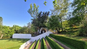 A landscaped garden with a white wall, a stone pathway, and a building in the background. - Polonezköy Country Club & Accommodation in the Wildlife Park (Beykoz)