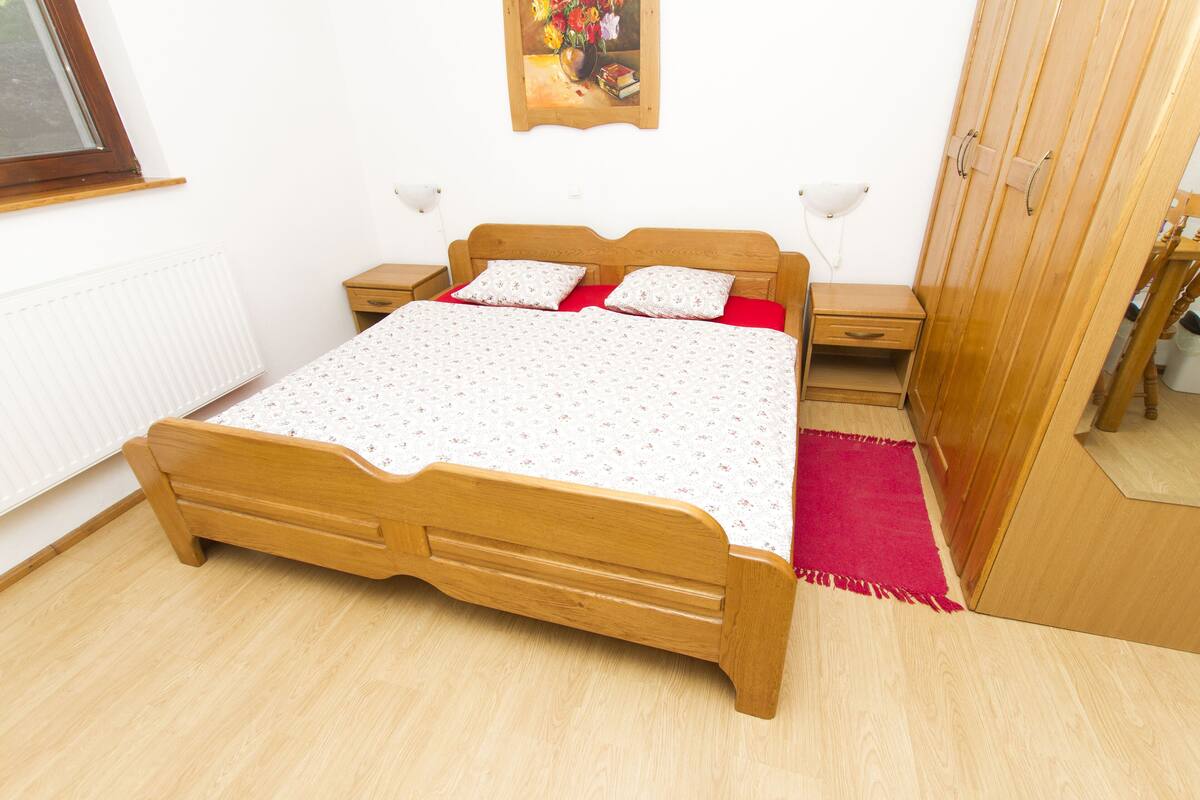A bedroom with a wooden bed, a nightstand, a dresser, and a radiator.