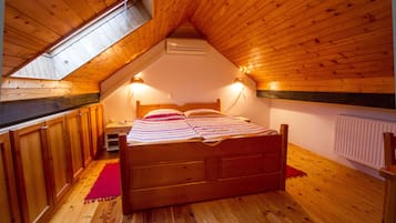 Un dormitorio acogedor en el ático, con techo de madera, una cama, una mesita de noche y una alfombra roja.