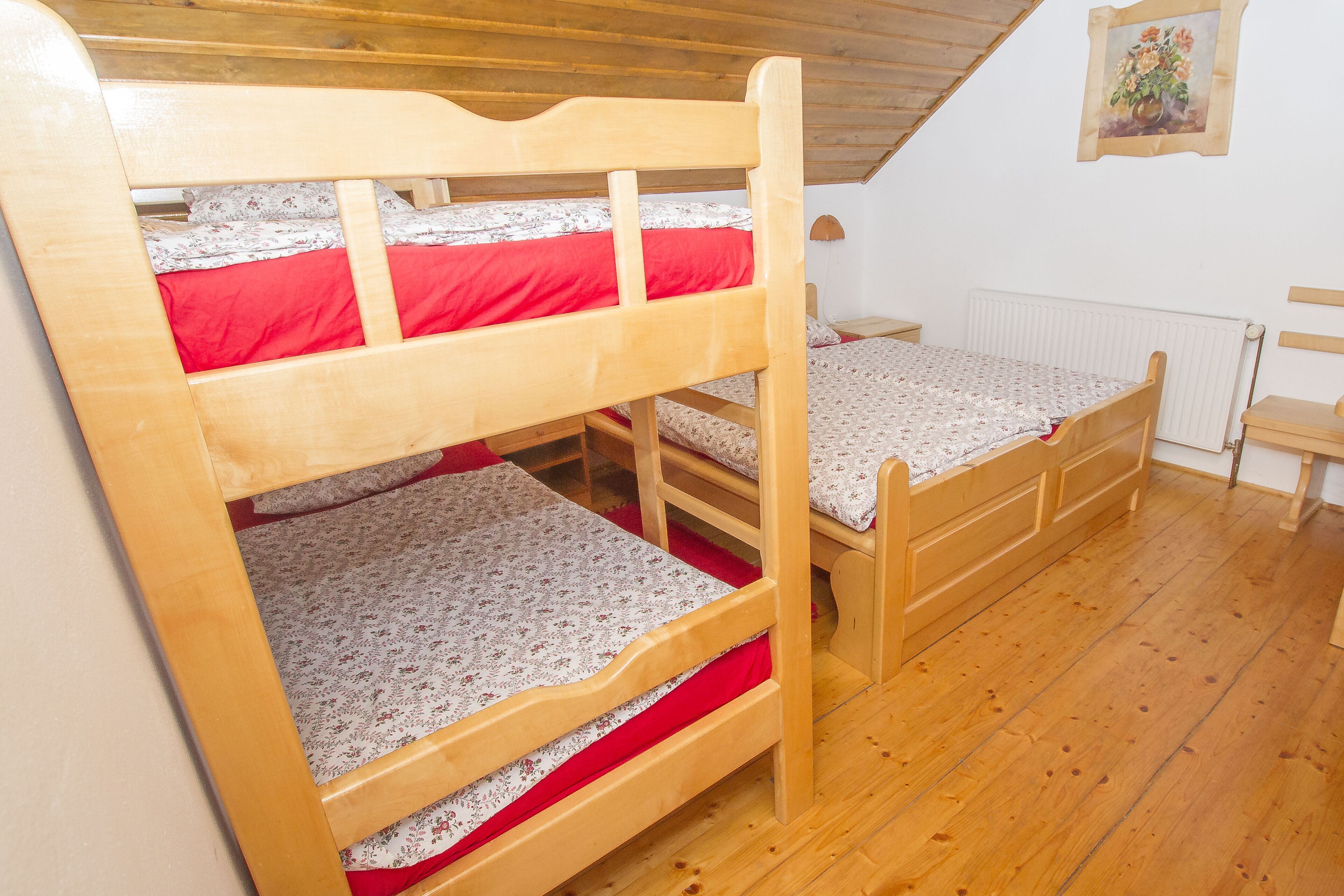 A bunk bed room with a wooden ceiling and a radiator.