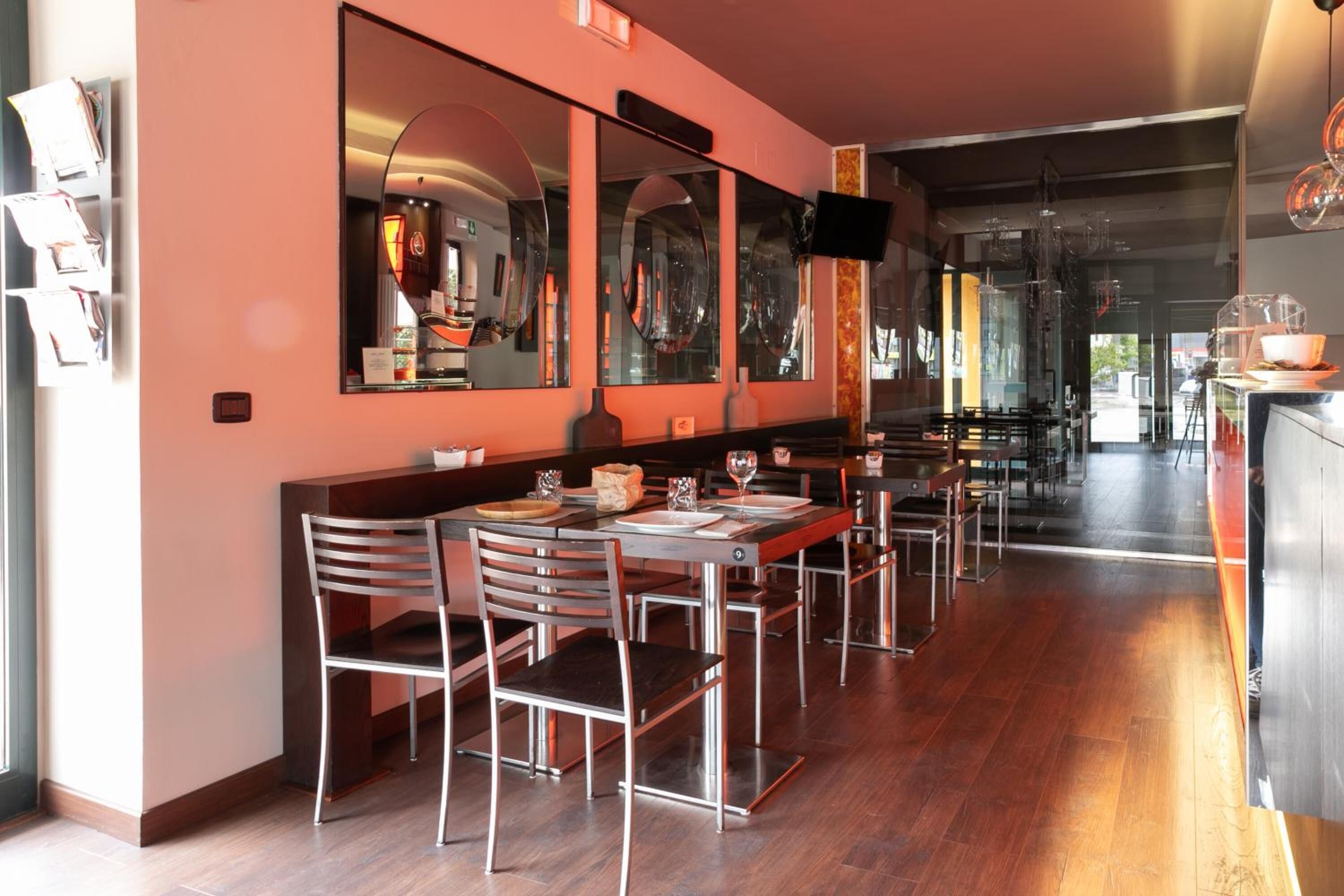 A restaurant with a long counter, multiple chairs, and a large mirror on the wall.