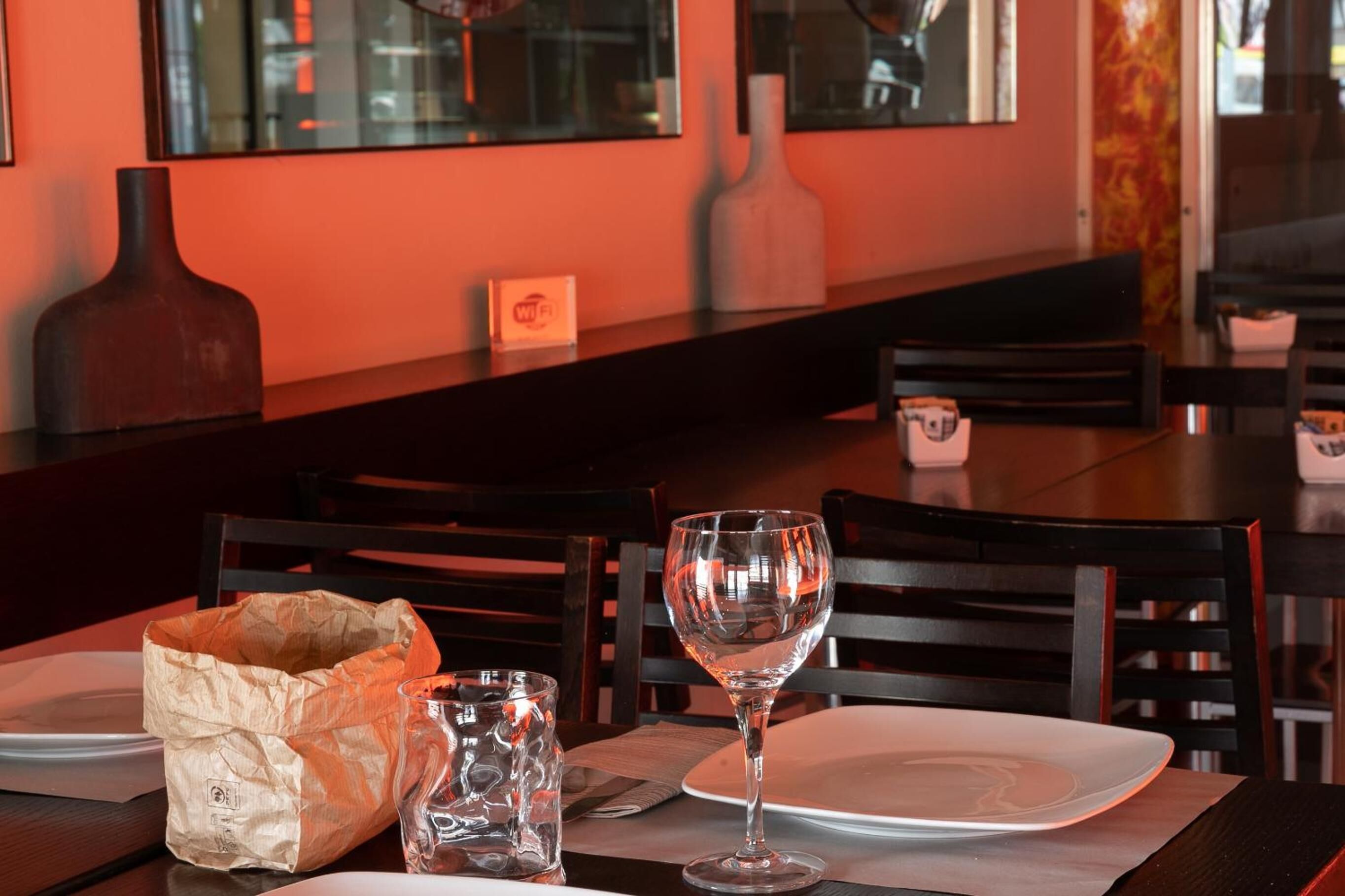 A restaurant table with a wine glass, a salt and pepper shaker, and a paper bag.