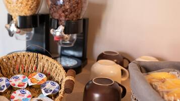 Un coin café équipé de deux distributeurs, un panier de pots de yaourt et un autre de viennoiseries.