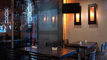 L’intérieur d’un restaurant présente une décoration moderne, avec notamment des lustres en verre suspendus, des tables en bois et des chaises.
