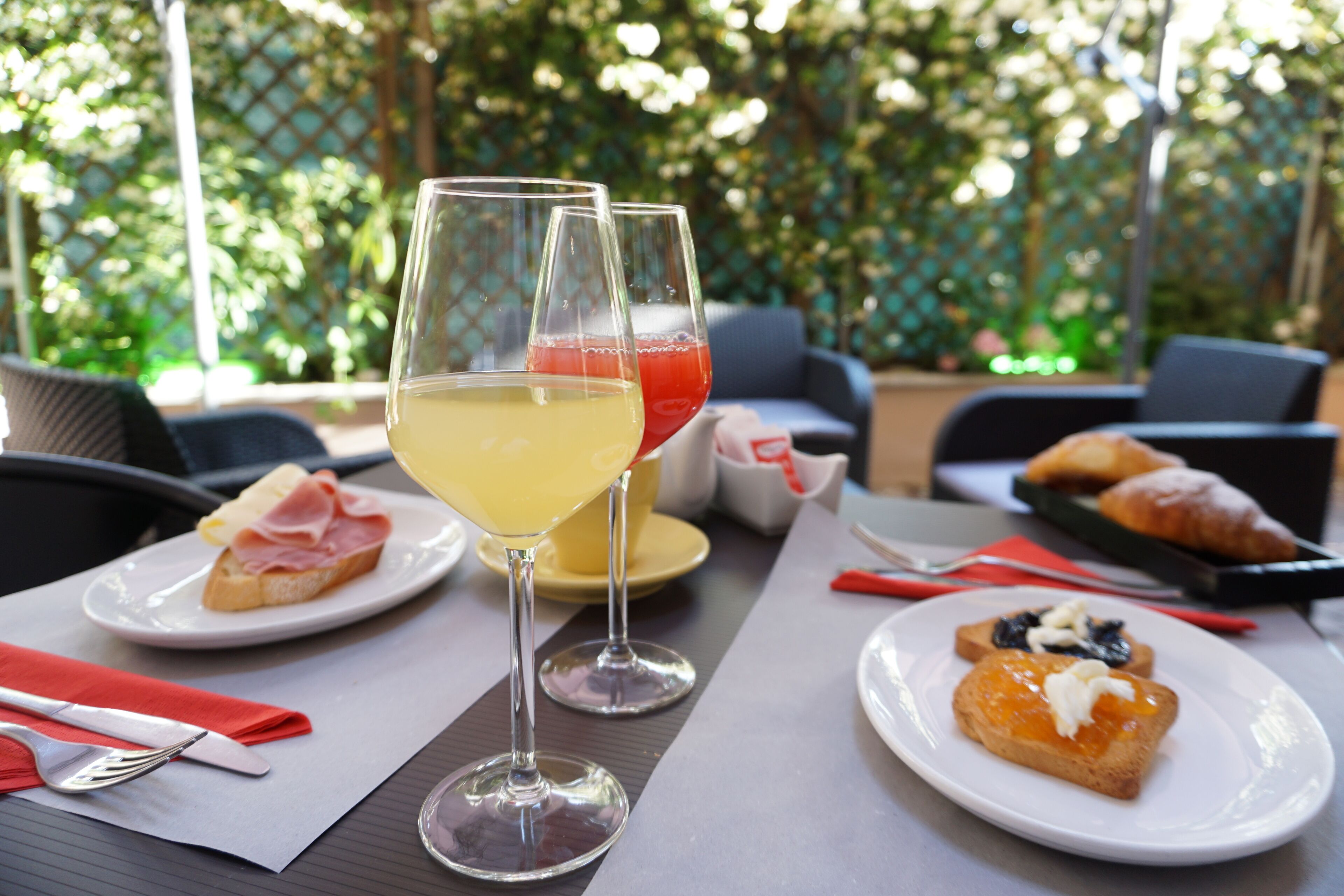 A table set with plates of food, two glasses of beverages, and cutlery.