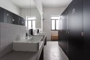 A modern bathroom with two sinks, a large mirror, and dark cabinets. - Hostel Alameda Exclusive House (Faro)