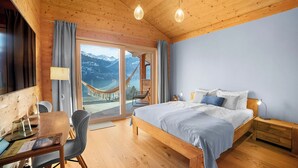 Une chambre dans une cabane en bois, comprenant un lit, des tables de chevet, un bureau et une chaise.