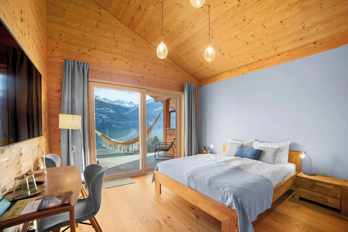 Une chambre dans une cabane en bois, comprenant un lit, des tables de chevet, un bureau et une chaise.