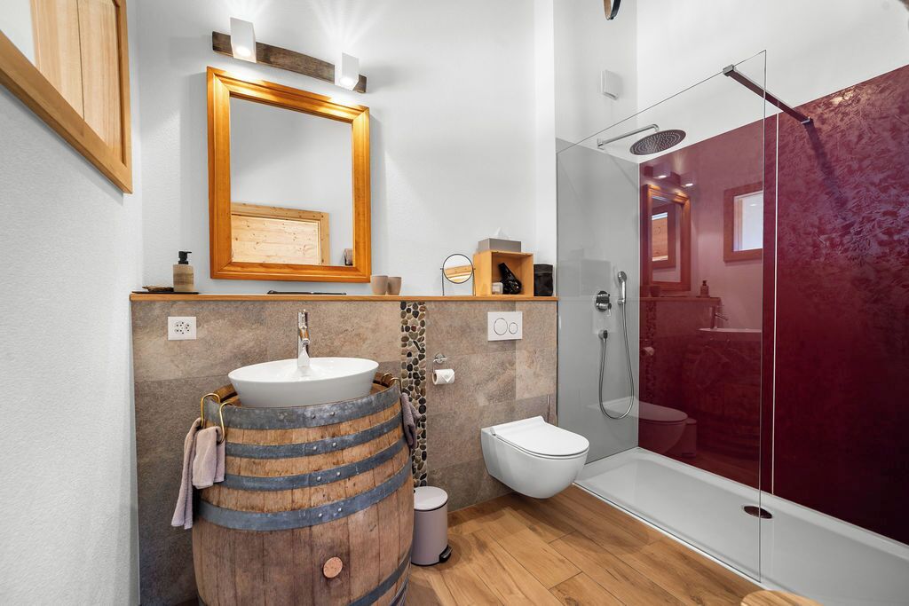 A modern bathroom with a wooden barrel sink, a glass shower enclosure, and a white toilet.